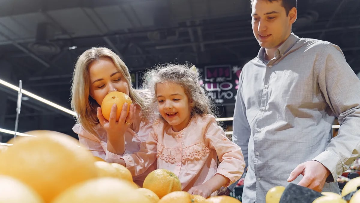 Family enjoying a cheerful shopping trip together at the grocery store, selecting fresh oranges.